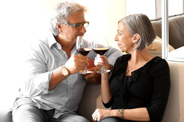 Aged couple drink wine on the couch