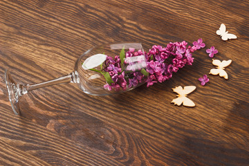 Wineglass with violet lilacs and butterflies