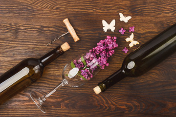 Wineglass with violet lilacs and bottles