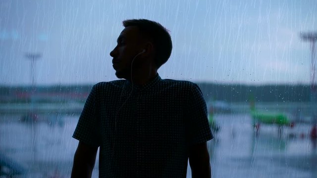 Silhouette of a young man at the airport against the window.