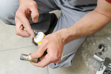 Plumber putting a paste sealant.