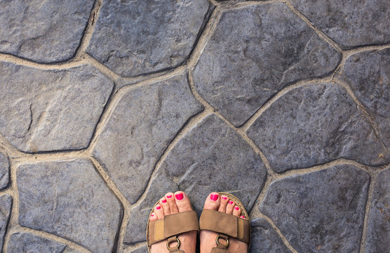Feet selfie from upper view of a woman traveler in sandal during a tour trip around the world. Tourist take a photo of her own leg.