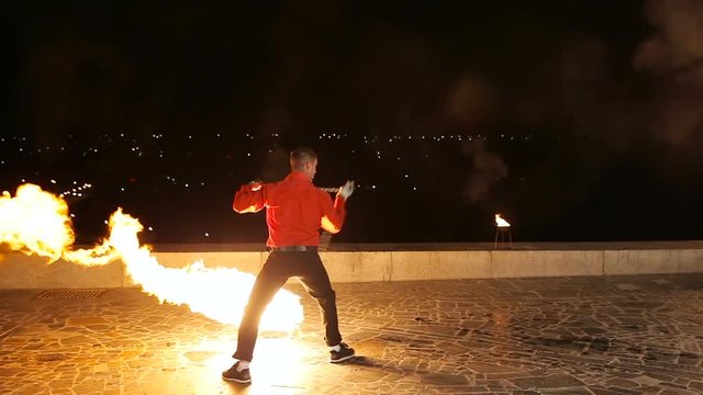 Artist man rotates the fireball.Man twist fiery circles on a fire show.Man does a fire performance.Fire show amazing at night.