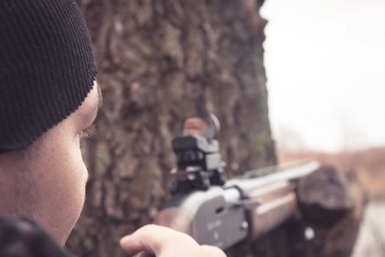 Man with gun aiming and prepared to make a shot during hunting
