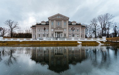 Large mansion or house stands on the former site of the fortress with a moat. Front of the house is reflected in the water.