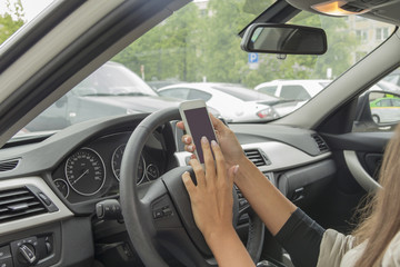 girl with a mobile phone behind the wheel in the saloon car