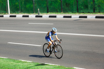 Naklejka premium Female cyclist rides a racing bike on road