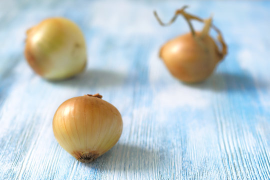 Three onions on white blue wooden background.