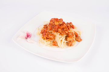 Spaghetti bolognese on a plate decorated with garlic cloves