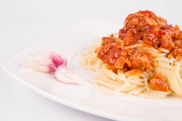 Spaghetti bolognese on a plate decorated with garlic cloves