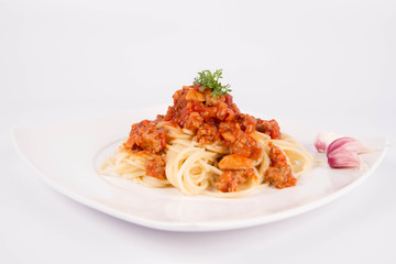 Spaghetti bolognese on a plate decorated with garlic cloves and cress