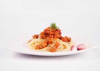 Spaghetti bolognese on a plate decorated with garlic cloves and cress