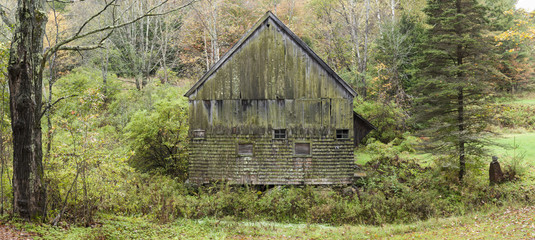 Old Vermont Shingled Barn: A panoramic view of an old wooden barn in a forest setting near Thetford, Vermont