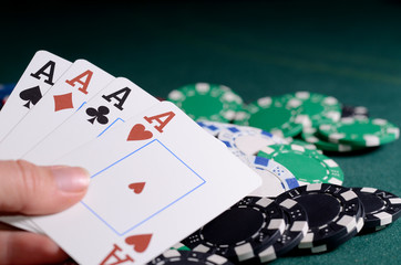 Chips stack and four of kind poker combination on a green background.