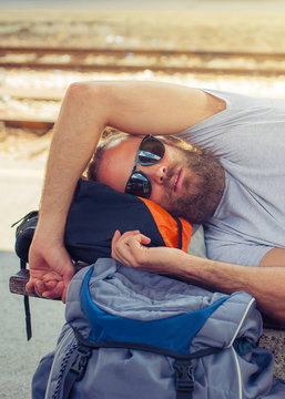 Closeup of male backpacker tourist napping on a bench