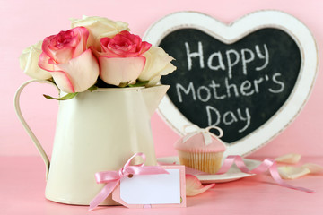 Happy Mother's day in a frame and roses in a vase on a pink background