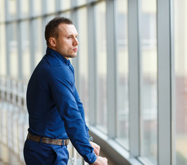 Businessman standing near the window and looking into it