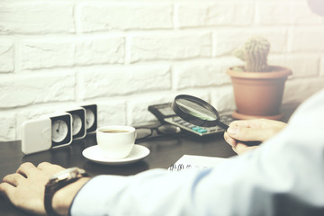 man, magnifying glass and paper