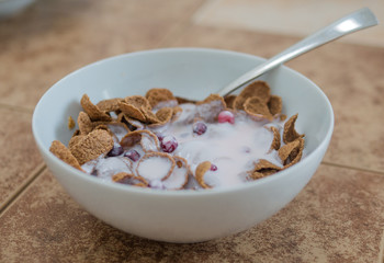 buckwheat flakes breakfast cereal with yogurt and cranberry in a white bowl