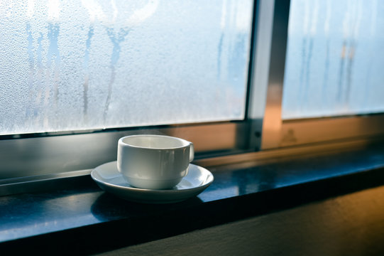 Coffee cup on fogged or frozen background window 