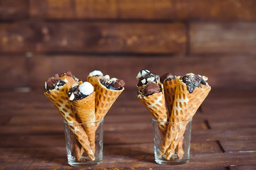 Tasty chocolate ice cream in waffle cone on brown wooden backgro