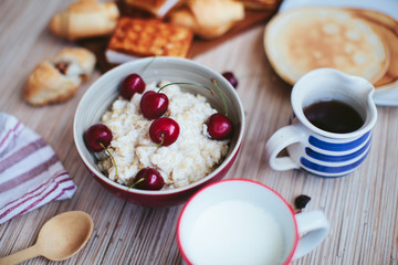rich breakfast of porridge with cherries and pastry