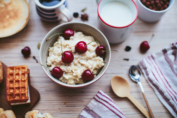 rich breakfast of porridge with cherries and pastry
