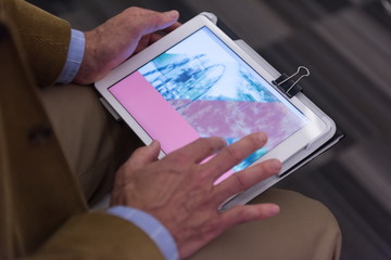 Closeup of mature hands holding tablet.
