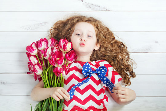 Cute little girl with red tulips and giving air kiss.