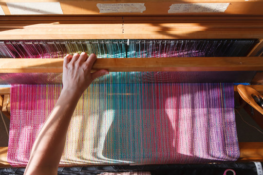 Hands of the woman weaving on a loom