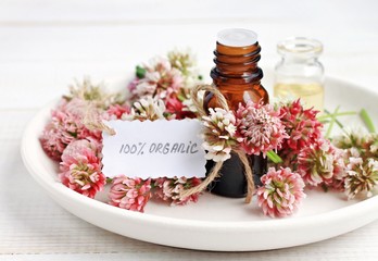 
Cosmetic bottle of aroma oils extract, clover flowers, paper tag handwritten text organic. Herbal skincare. 