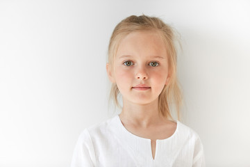 Portrait of angel-like child in white morning light in studio. Little European girl with blond hair...