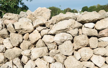 Ancient wall from stones on a background of blue sky and trees
