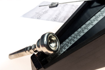 Metronome and mouthpiece of a trumpet isolated on a blank white