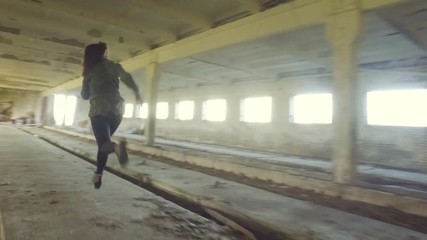 The girl run away from killer in abandoned building through the hallway. Back view horror dark mood. Steadicam shot. Smooth tracking. Old abandoned place. Slow motion.