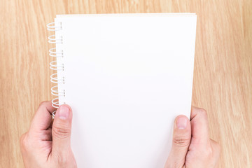 Close up Two Hand holding empty white open book above wood desk