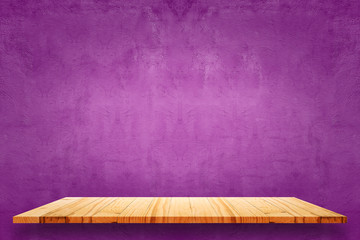 Empty top of wooden shelves and purple cement wall background.
