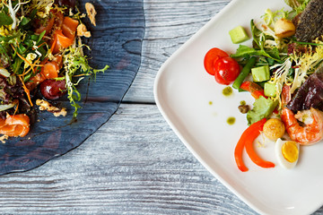 Salad on plates. Salad with tomatoes and fish. Pieces of walnut and shrimp. Popular salads from European cuisine.