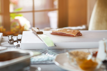 Piece of meat and knife. White cooking board with knife. Duck breast for steak. Main ingredient of special dish.