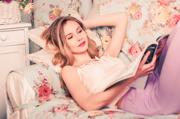 beautiful young girl lying on the couch reading a magazine