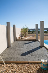 The pillars of a pool side pergola during construction. Wet concrete can be seen in the future terrace area.