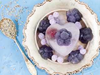 Lavender ice cream flowers made of frozen orange and lemon juice with lavender syrup in a silver bowl on blue background