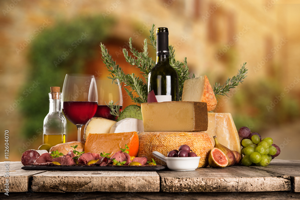 Wall mural delicious cheeses with wine on old wooden table.