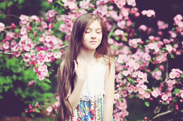 Obraz na płótnie Canvas Kid girl in blooming garden