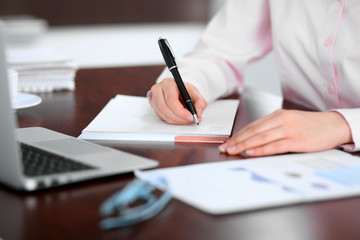 Closeup of a business woman writing in a notebook