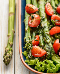 Appetizer - delicious vegetarian salad with green asparagus, tomatoes and vinaigrette dressing.