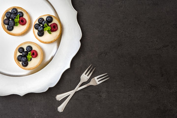 Delicious tartlets with raspberries and blueberries on a tray.
