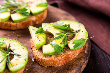 Toast with avocado, herbs on wooden board