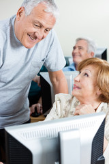 Senior Man Assisting Woman In Using Computer