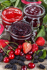 strawberry, cherry and mulberry jam on a rustic table